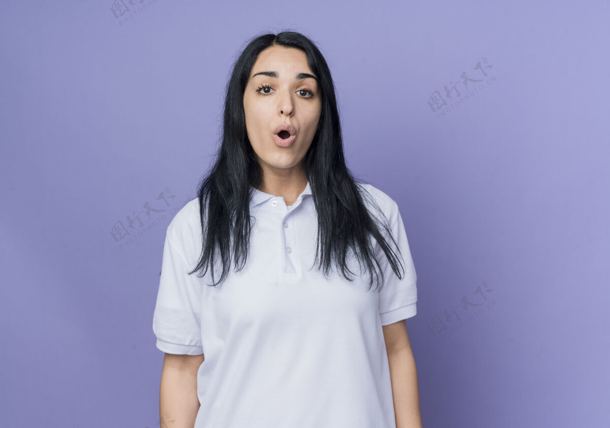 紫色惊讶的年轻黑发白人女孩孤立地站在紫色的墙上黑发站起来惊喜