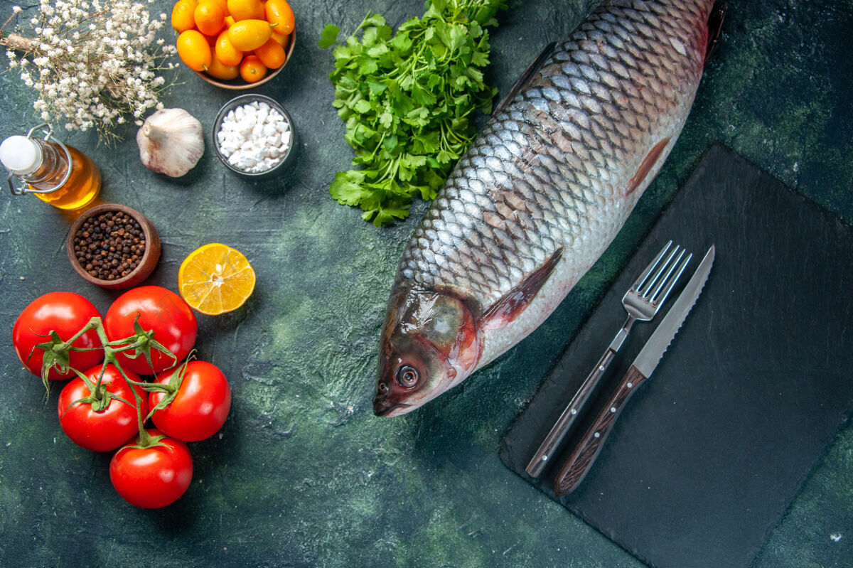 深色顶视图新鲜的生鱼与西红柿和绿色的深色背景景观健康蔬菜