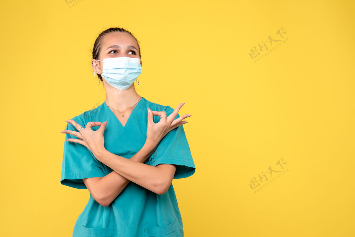 正面黄墙上穿着医疗服 戴着无菌口罩的女医生的正面图面具医生医院