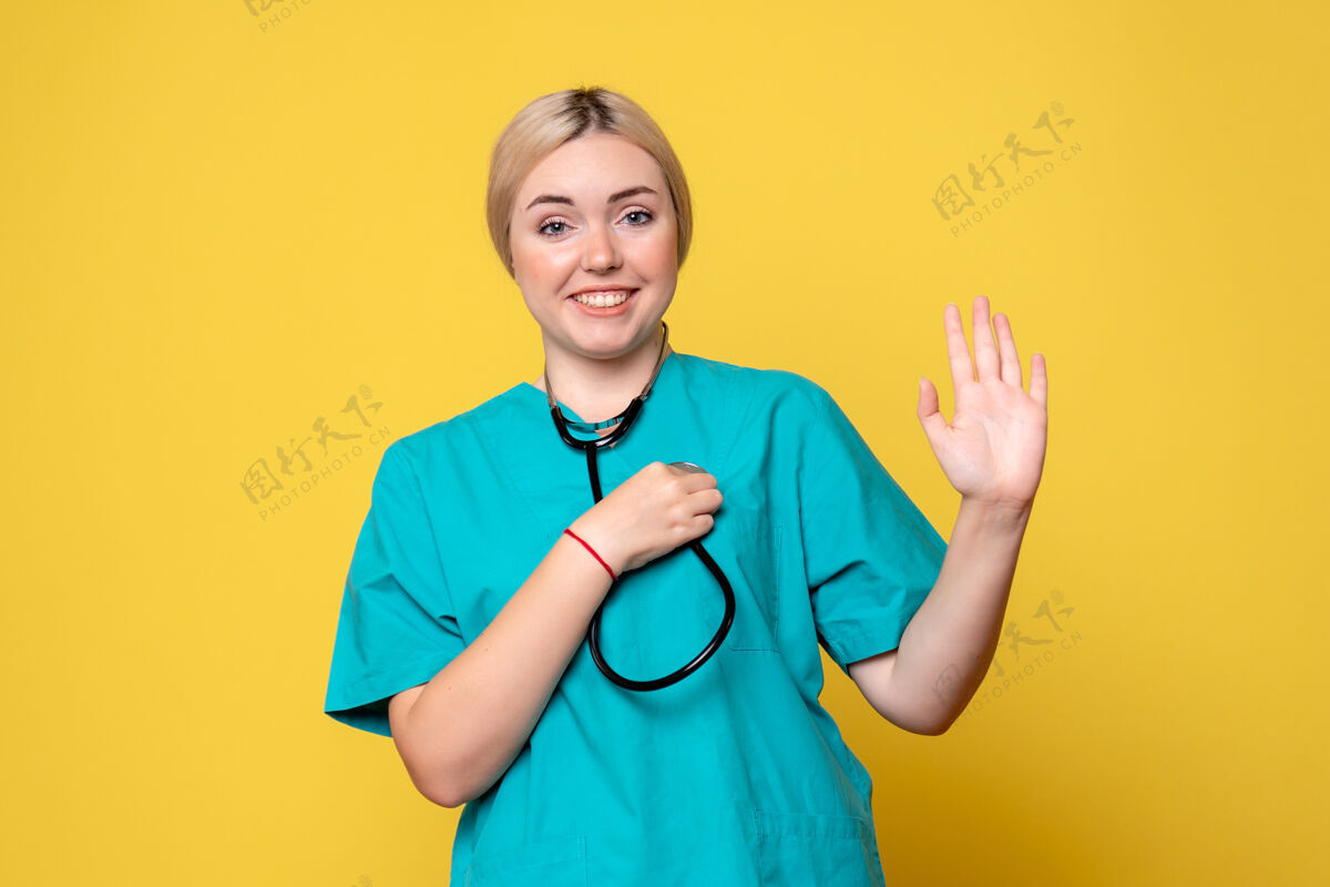 护士黄色墙壁上穿着带听诊器的医用衬衫的女医生的正视图听诊器医疗器械衬衫
