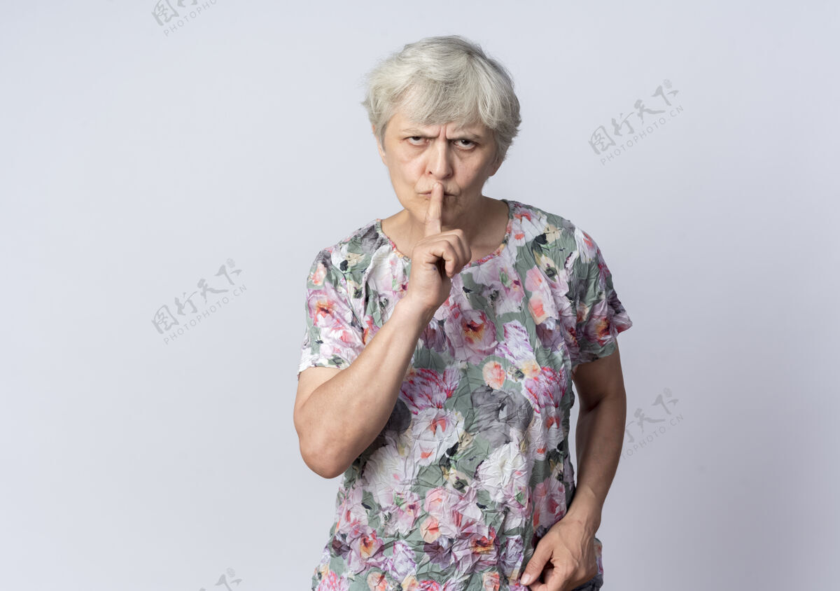 手势严肃的老妇人把手指放在嘴上 示意安静的标志孤立在白墙上嘴巴手指安静