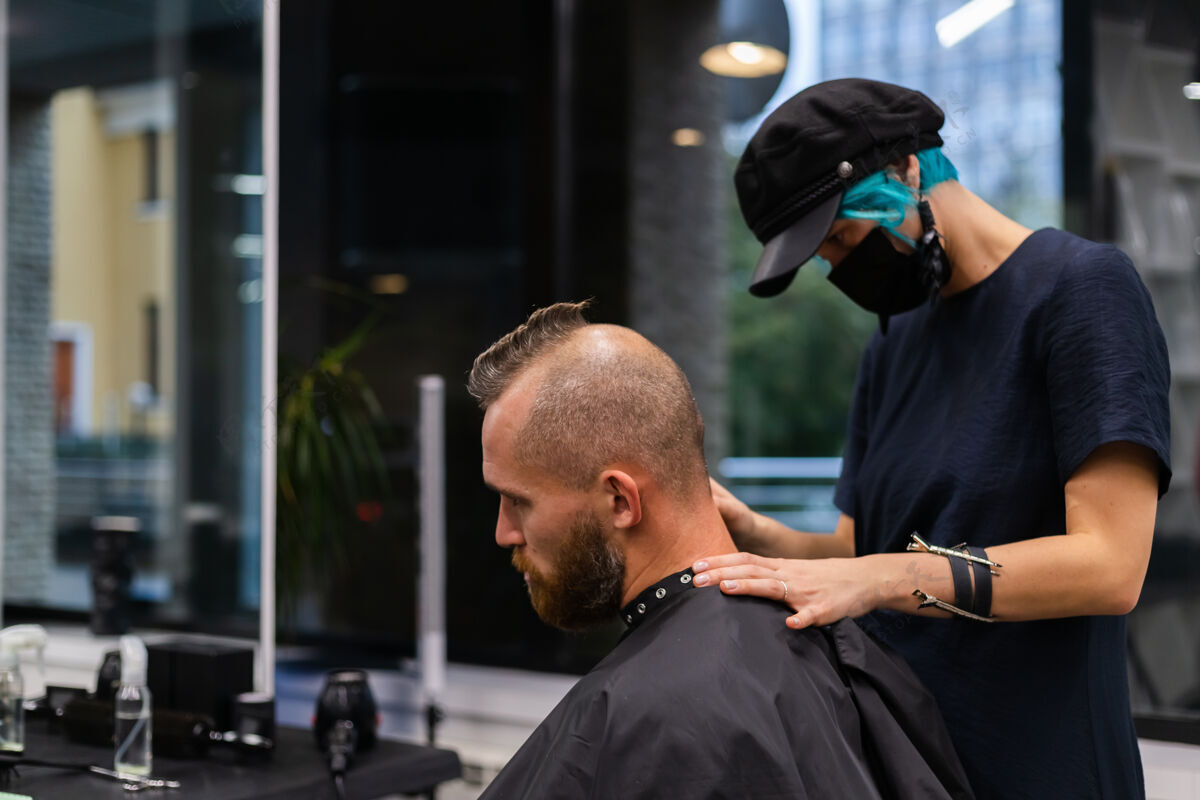 男性专业美发师戴着防护面罩 在美容院为欧洲胡须野蛮男子理发肖像修剪理发师