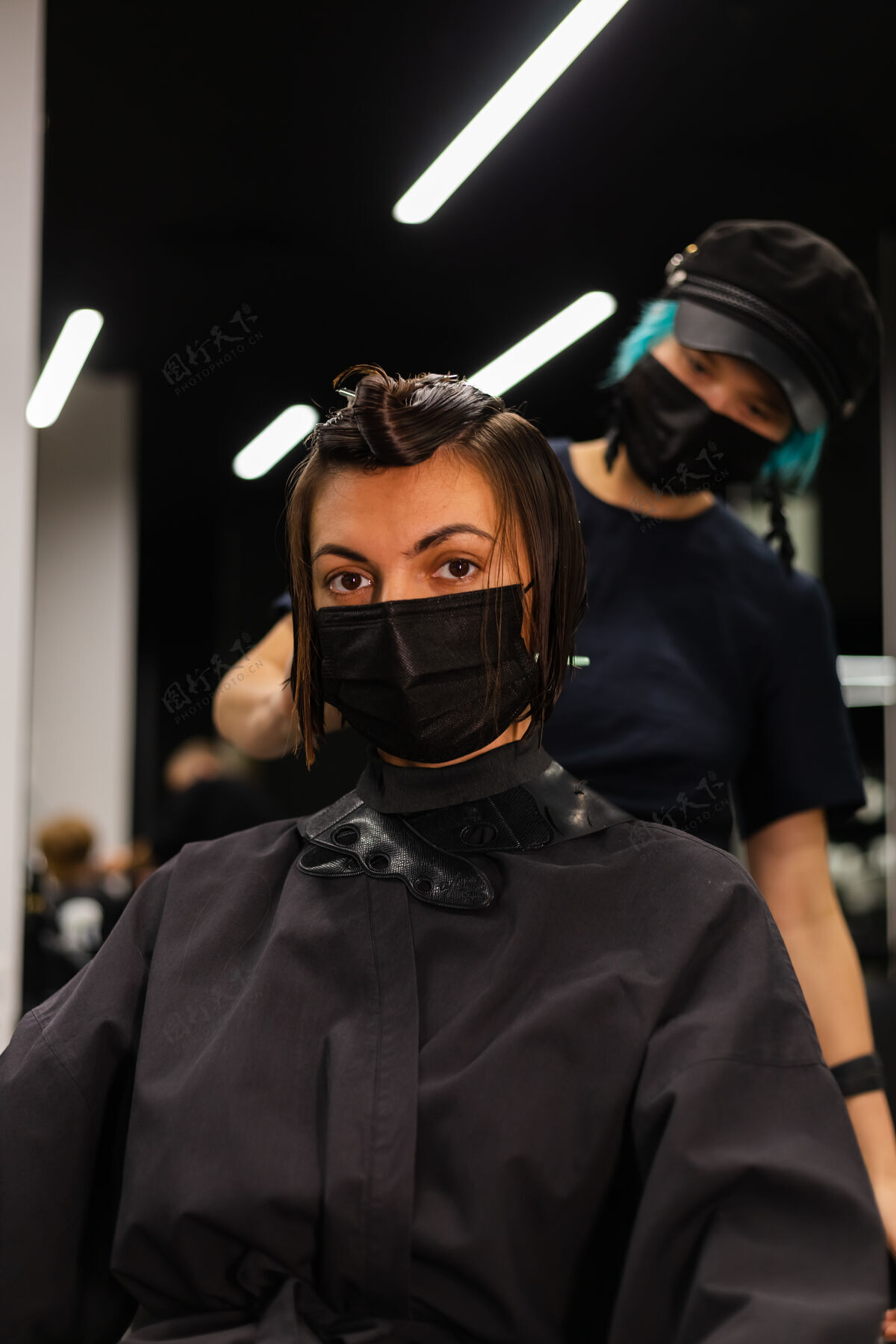 脸一个专业的女理发师给客户理发这个女孩戴着面具坐在美容院里人发型师面部