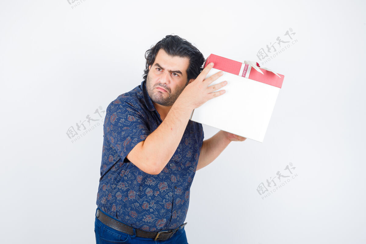 衬衫成熟的男人拿着礼品盒在耳边 穿着衬衫 看上去很好奇 正对着窗外老年人休闲好奇