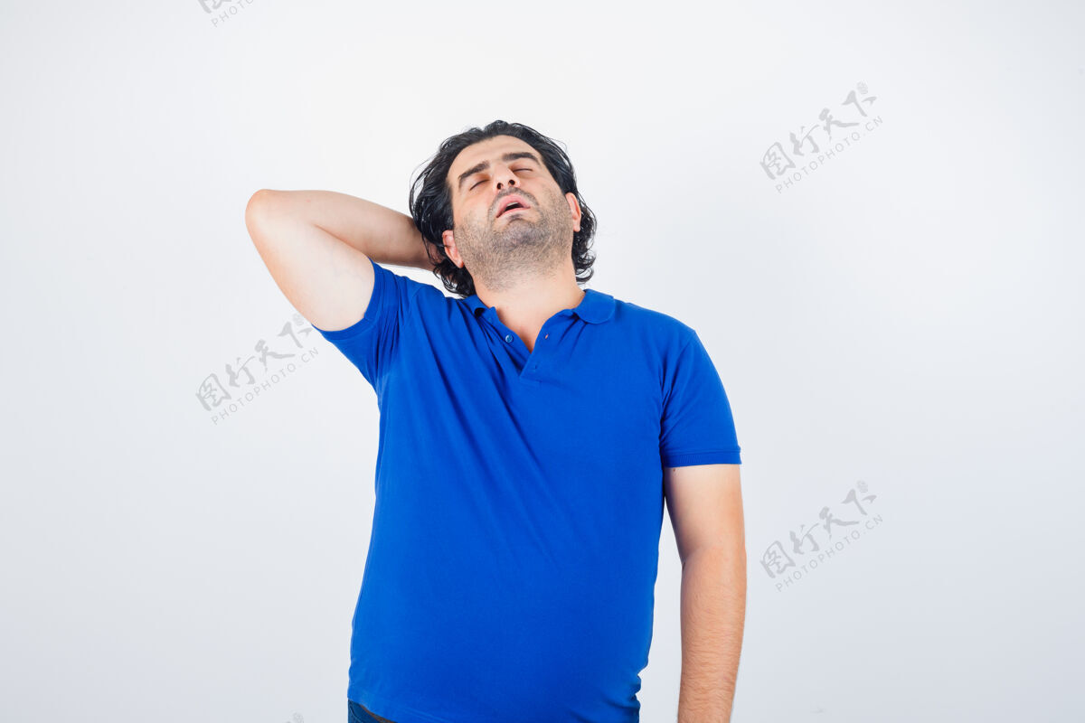 放松穿着蓝色t恤的成熟男人 手拉在脑后 看起来很困倦 前视图疲惫头表情