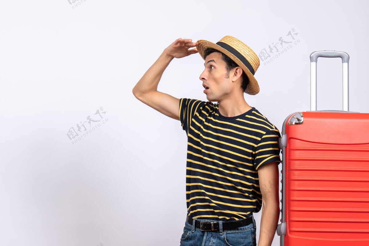 工作室前视图：站在红色手提箱旁的戴草帽的年轻人快乐前面红色