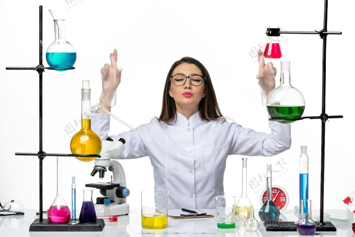 人前视图穿着白色医疗服的女化学家坐在不同的解决方案上 背景是白色的科学病毒实验室病毒大流行解决方案西装观点