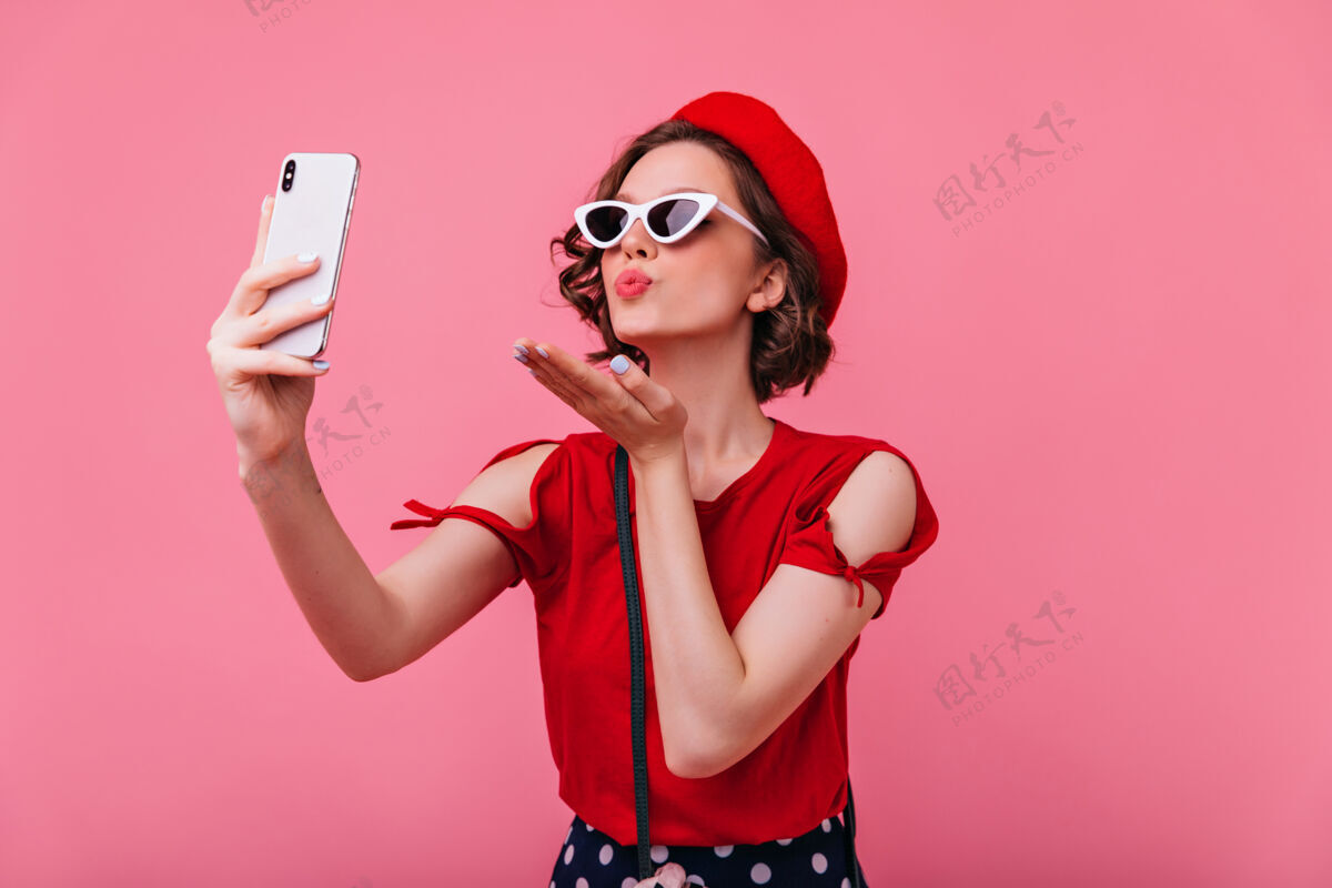 放松美丽的法国女人在拍自己的照片时送上了空气之吻室内浪漫的卷发女士在betet自拍的肖像休闲时尚快乐