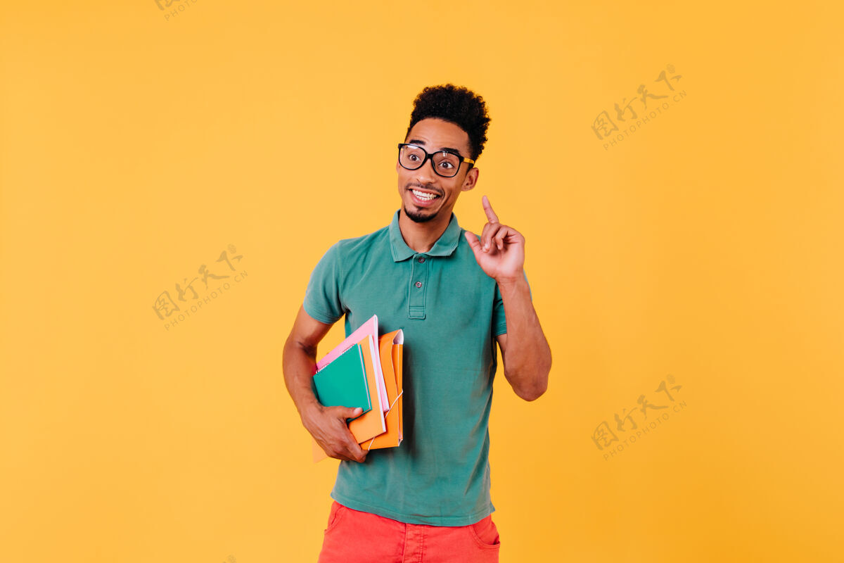 室内聪明的国际学生站着照片中欣喜若狂的非洲男子戴着时髦的眼镜看书笔记本学术现代