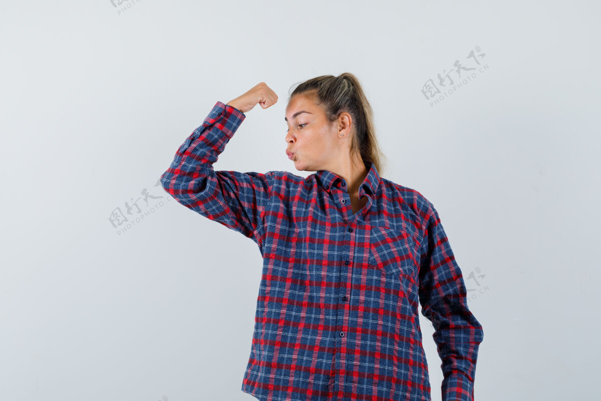 一穿着格子衬衫展示手臂肌肉的年轻女士 看起来很自信前视图肖像衬衫前面