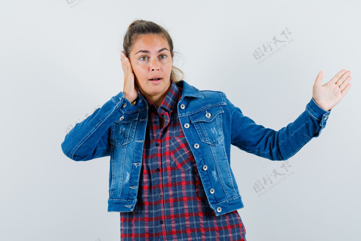 休闲年轻女子展示着什么 穿着衬衫 夹克 手放在耳朵上 神情沉思前视图衬衫夹克耳朵