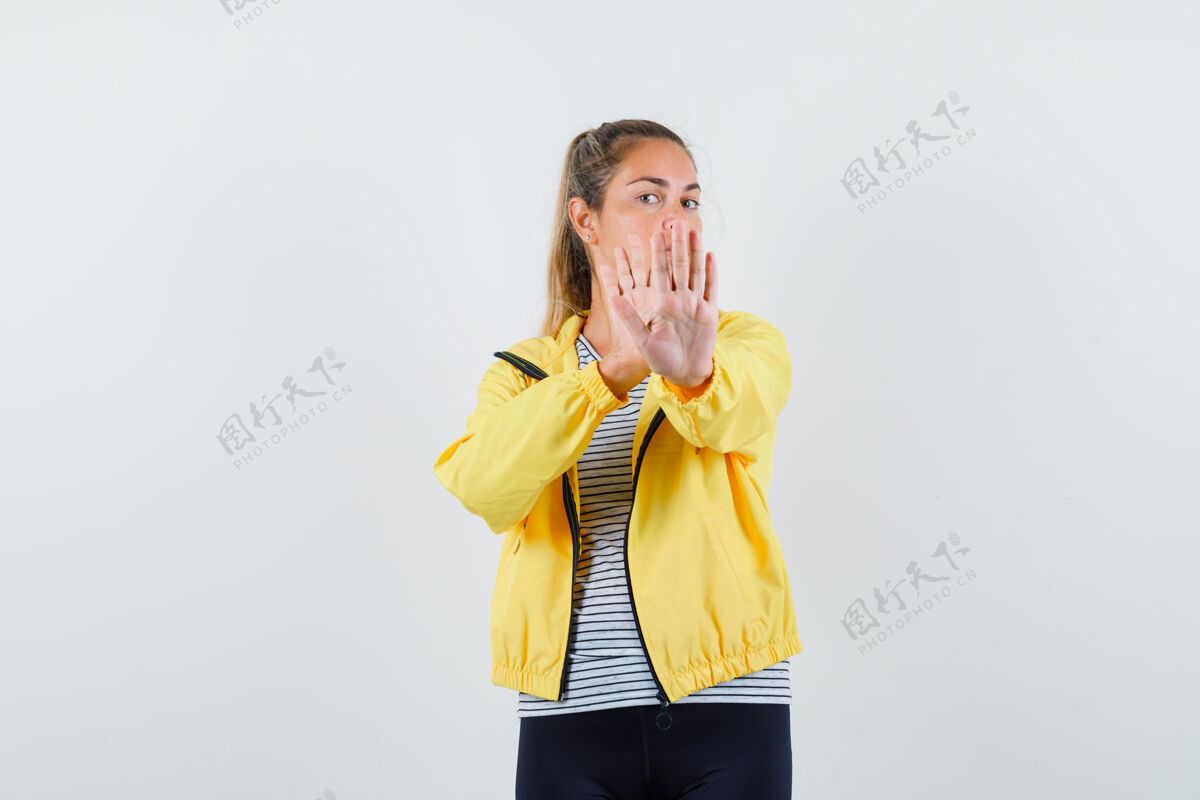 视图穿着夹克衫的年轻女性 t恤上显示着停下来的姿势 看起来很自信 正面视图成人显示手势