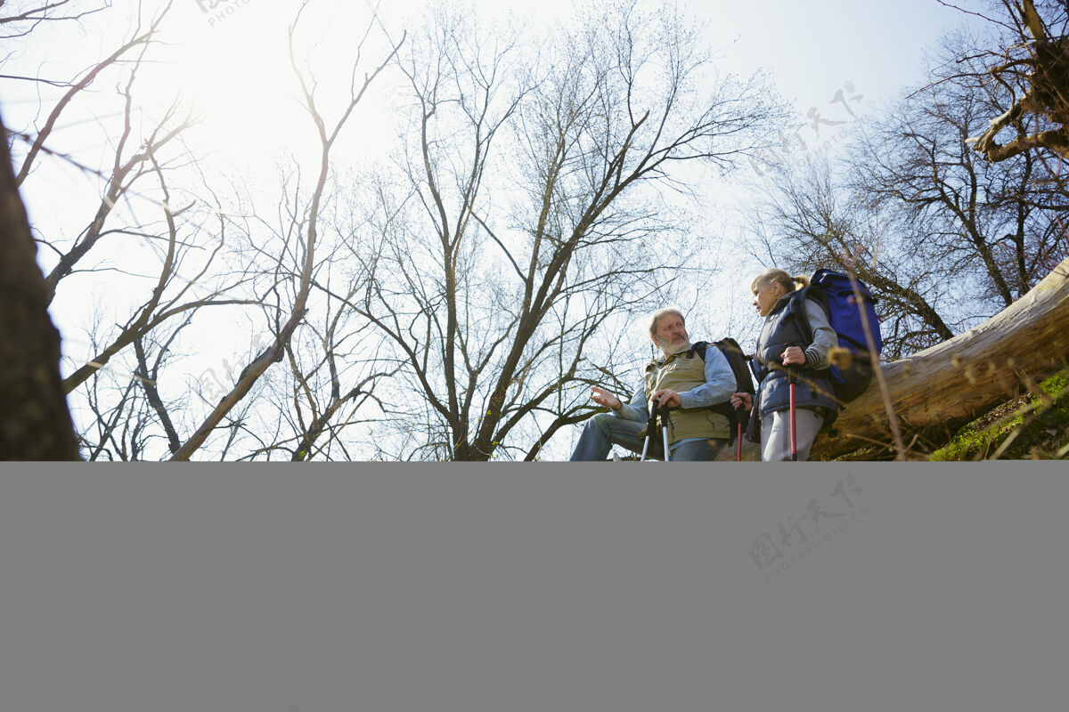 发现私人谈话一对穿着旅游服装的老年夫妇在阳光明媚的日子里走在树旁的绿色草坪上旅游理念 健康的生活方式 放松和团聚年龄欢呼活跃