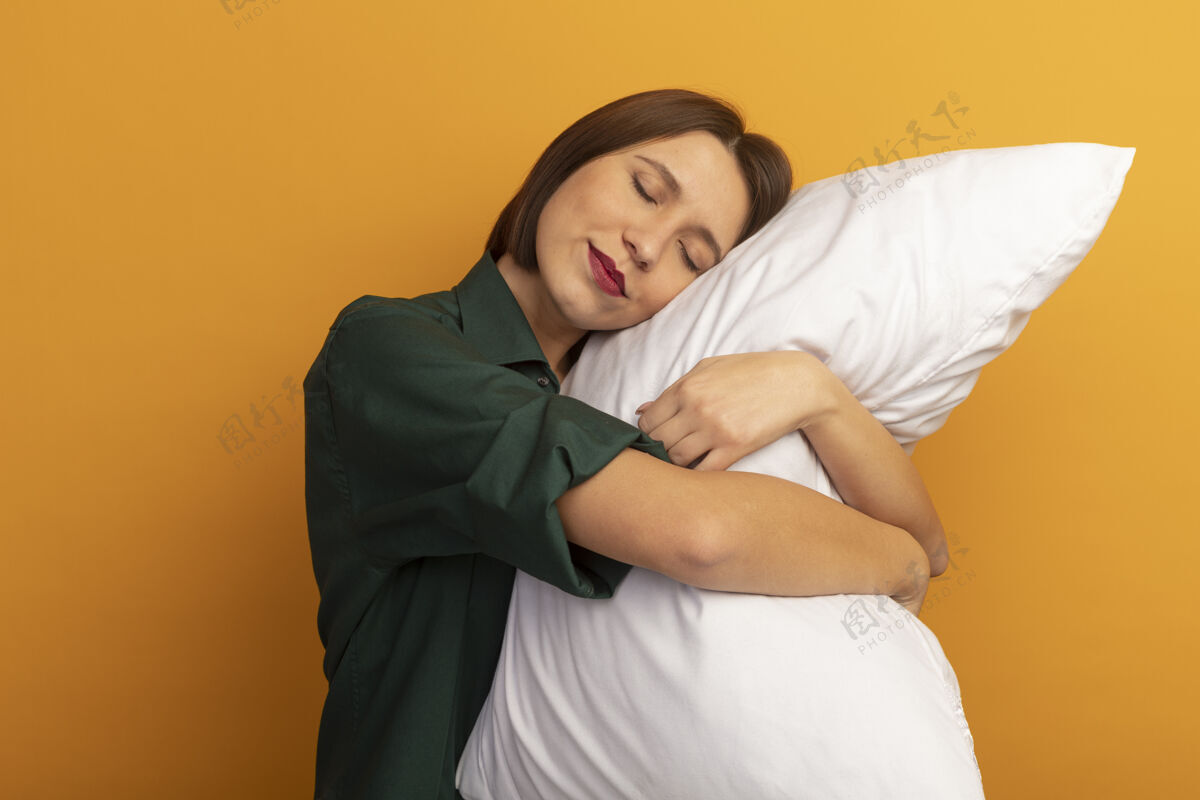 姿势昏昏欲睡的漂亮白种女人把头放在桔子上的枕头上枕头年轻黑发