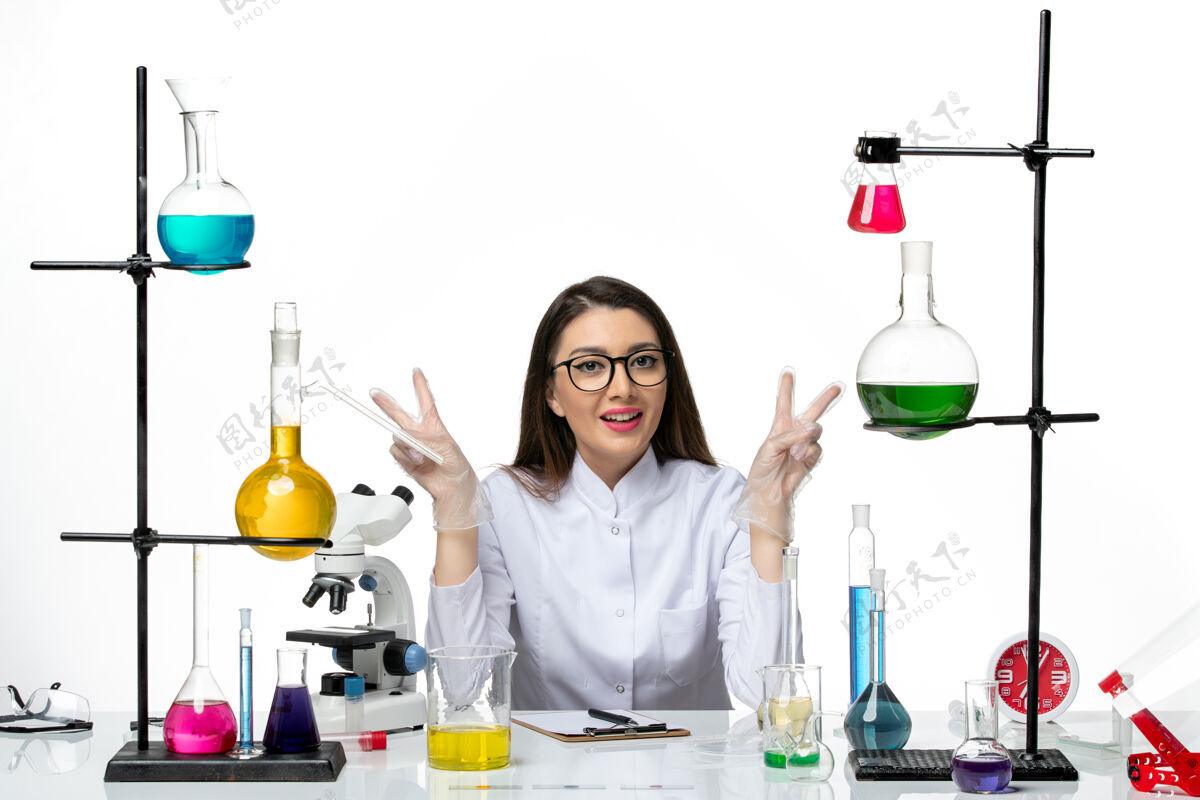 科学前视图穿着白色医疗服的女化学家坐在白色背景上愉快地摆姿势实验室病毒冠状病毒大流行科学实验室医学实验室