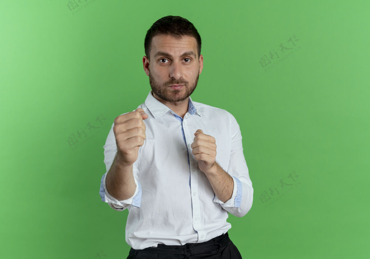 拳自信的帅哥握着拳头准备在绿色的墙上挥拳绿色自信拳头