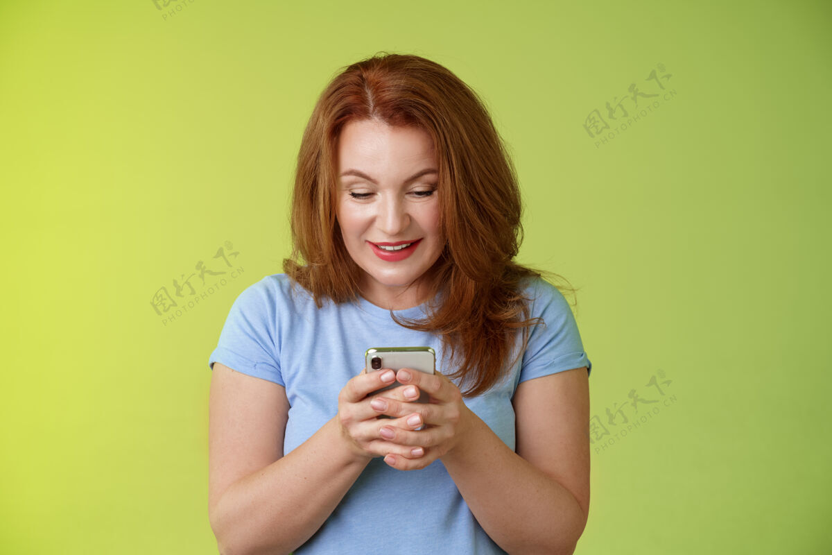 红发好奇兴奋诱惑红发中年女子网上购物智能手机手持手机表情愉悦娱乐小玩意屏幕笑容可掬玩游戏发现完美应用短信微笑电话