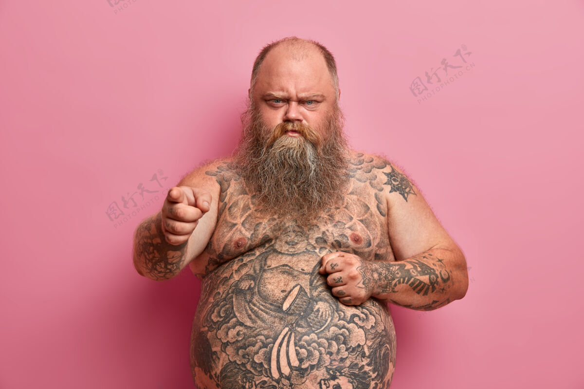 沮丧愤怒的过重男人把手放在裸露的大肚子上责怪你 听到关于他自己的攻击性的话 身上有纹身 胡子又长又粗 要节食不安肚子罗西