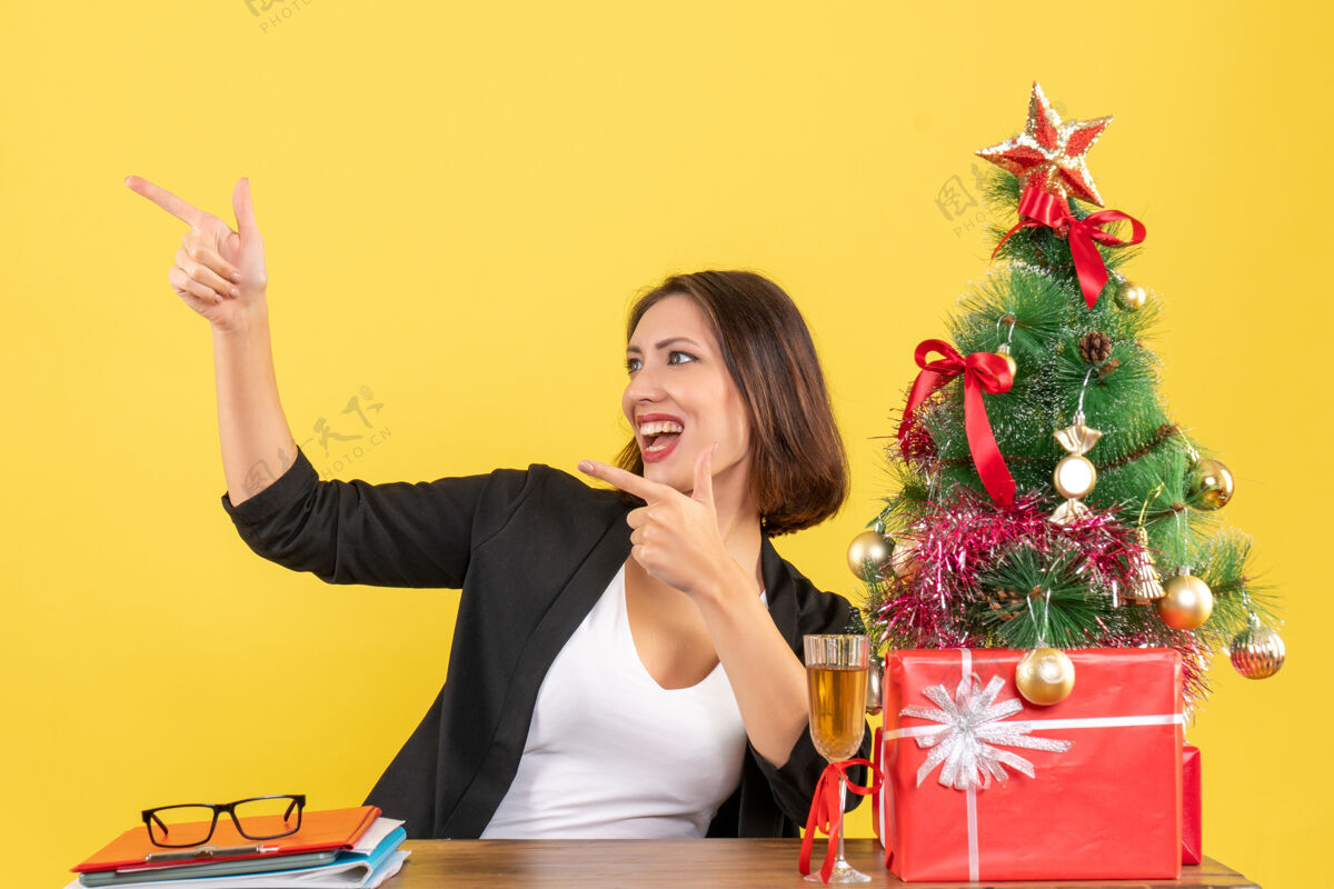 微笑新年的心情 美丽的商务女士开心地指着东西 坐在办公室的桌子旁坐欢呼快乐