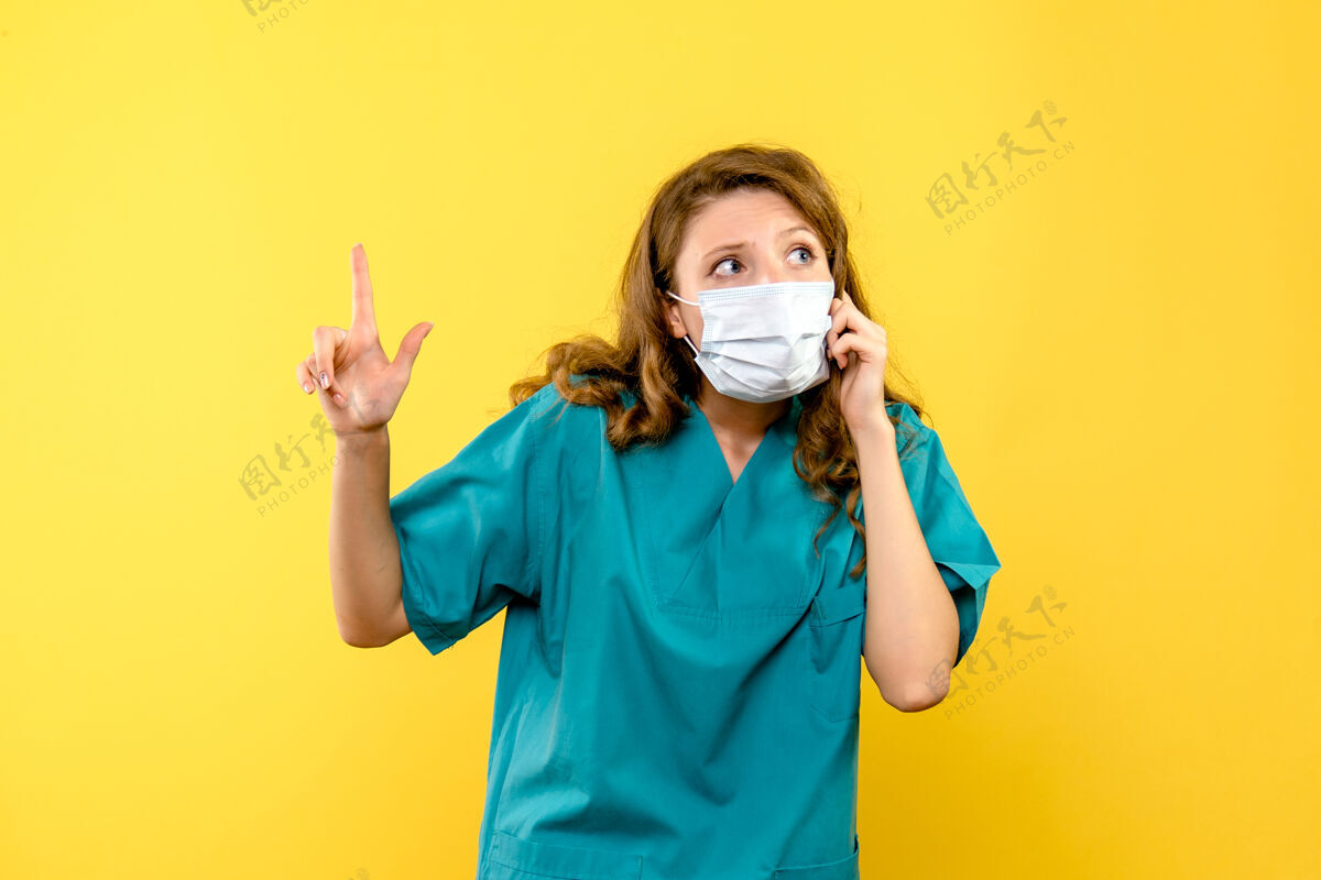 防护罩黄墙上戴着面具的女医生的正视图制服专业药