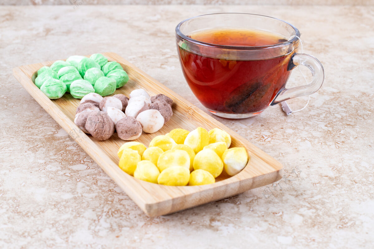 糖果一杯茶和各式各样的糖果装在一个小木托盘里美味小吃糖果