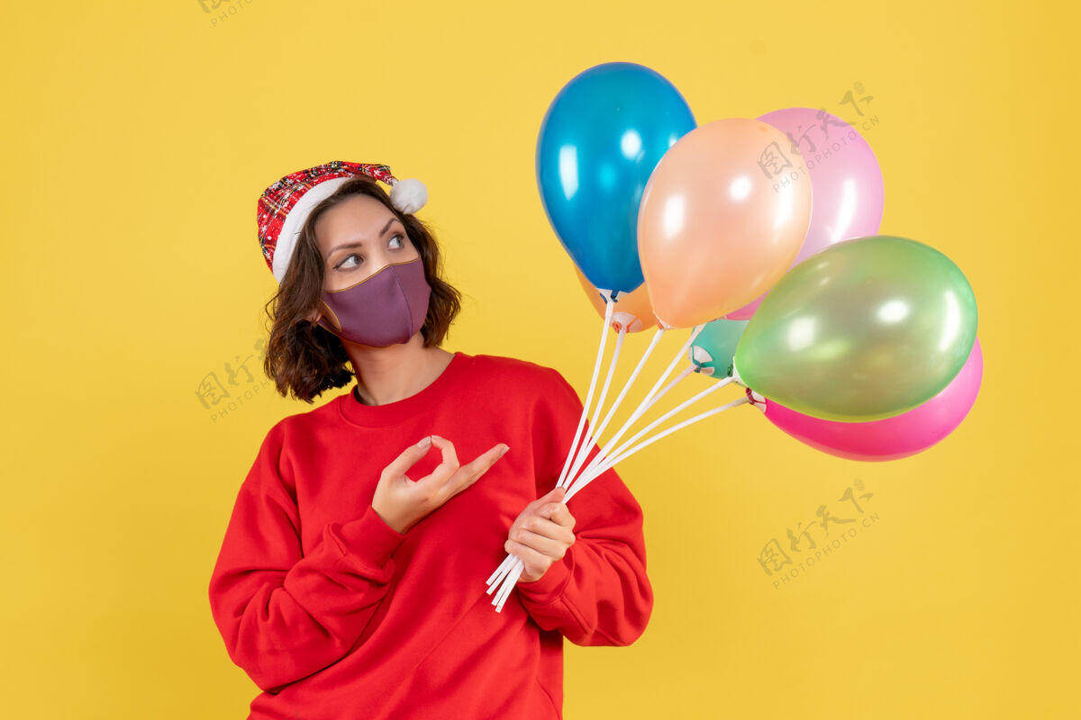 颜色正面图年轻女性拿着气球 戴着黄色的无菌面具女人气球消毒