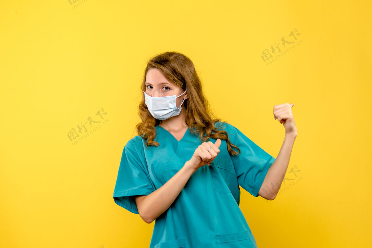 绝育黄色墙上戴着无菌口罩的女医生的正视图保健脸病毒