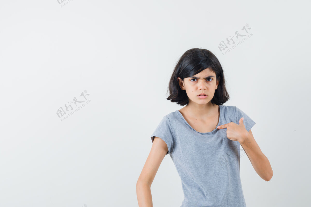肖像小女孩指着自己的t恤衫 看着困惑前视图脸人欢呼