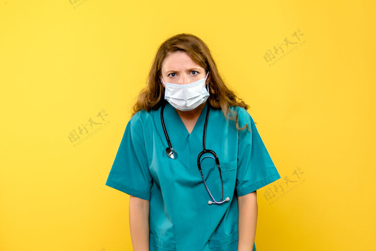 医疗保健黄色墙上戴着无菌口罩的女医生的正视图医疗器械面罩人