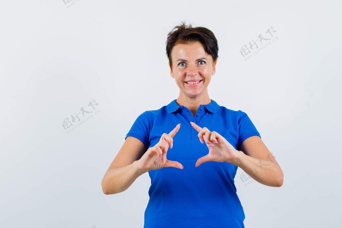 漂亮成熟的女人在蓝色t恤上做框架动作 看起来很开心正面视图提升成熟手势
