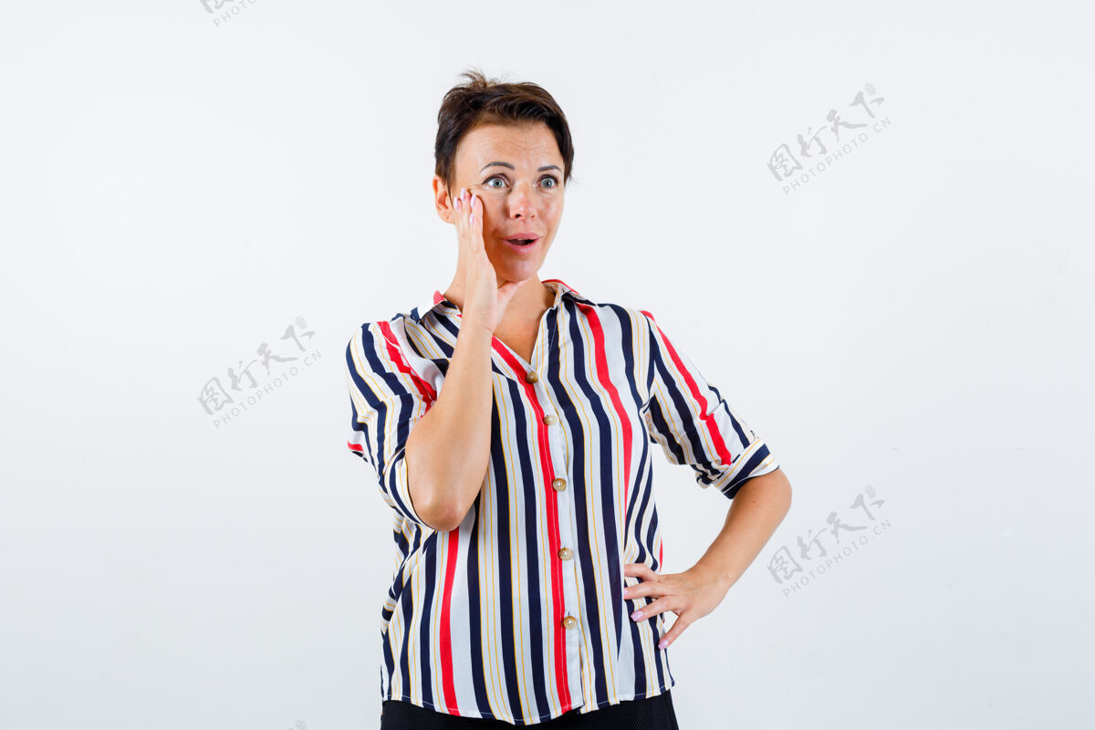 抱着成熟的女人一只手放在腰上 另一只手放在嘴边 穿着条纹衬衫 看起来很惊讶前视图女人自信人