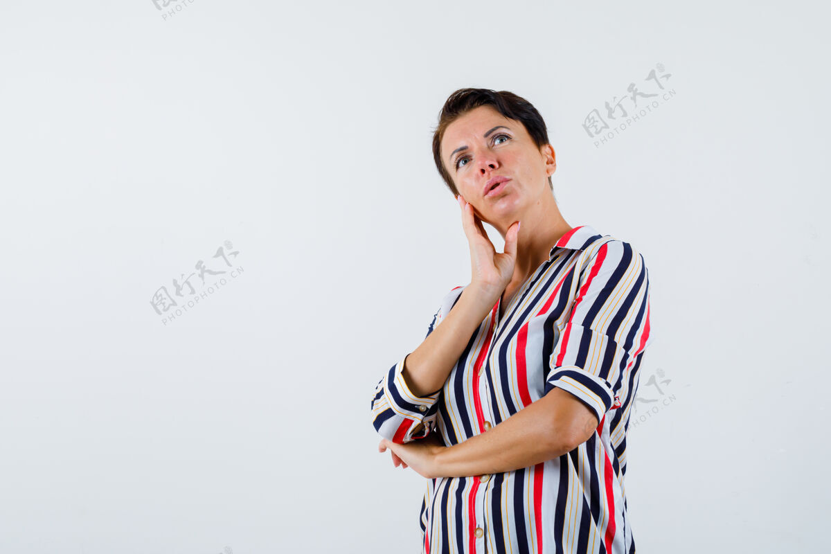 脸颊成熟的女人面颊靠在手掌上 一只手放在手肘上 穿着条纹衬衫 神情沉思前视图条纹持有衬衫