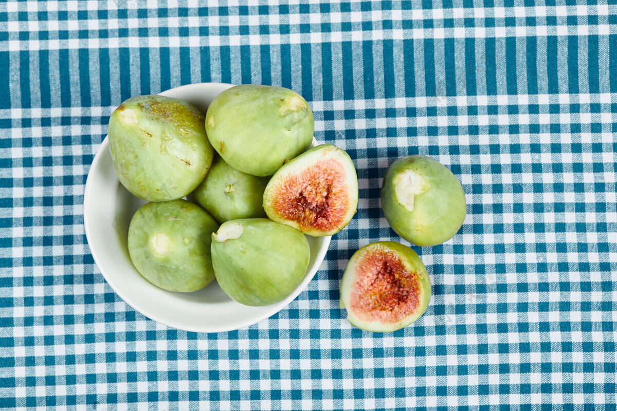 美味绿色无花果在一个白色的碗和一个木制的桌子上与蓝色桌布高品质的照片热带食品水果