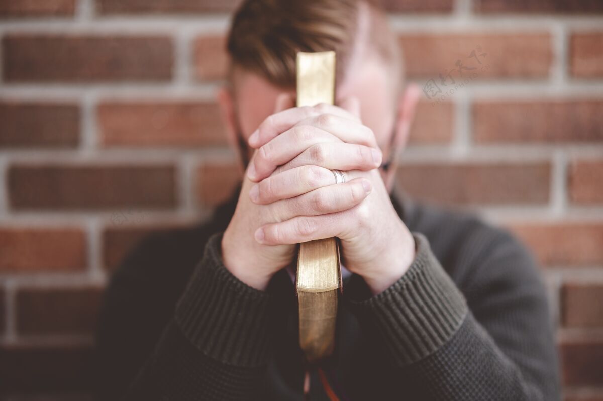 宗教郁闷的年轻男子靠墙坐在地上拿着圣经抑郁脸烦恼