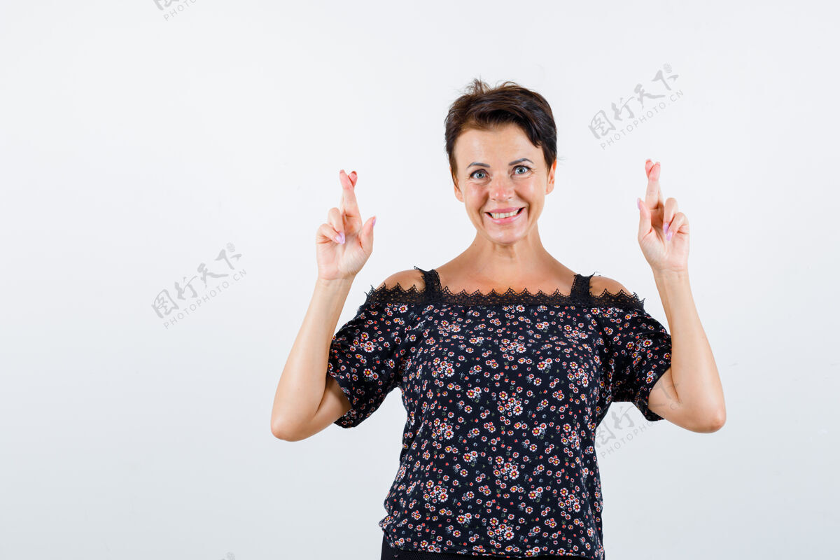 微笑成熟的女人穿着花衬衫 黑色裙子交叉着手指 看起来很快乐 正面视图交叉健康快乐