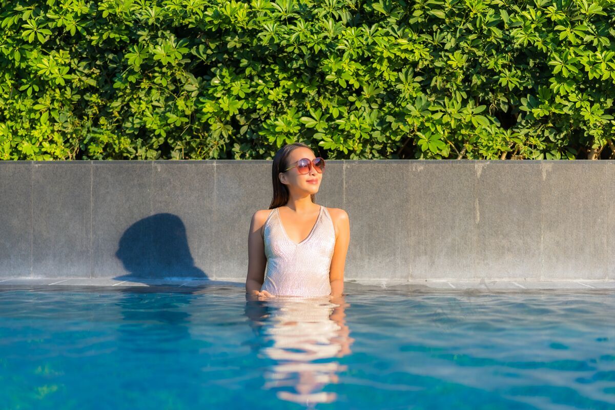 阳光美丽的年轻女子在游泳池放松的画像女性热带乐趣