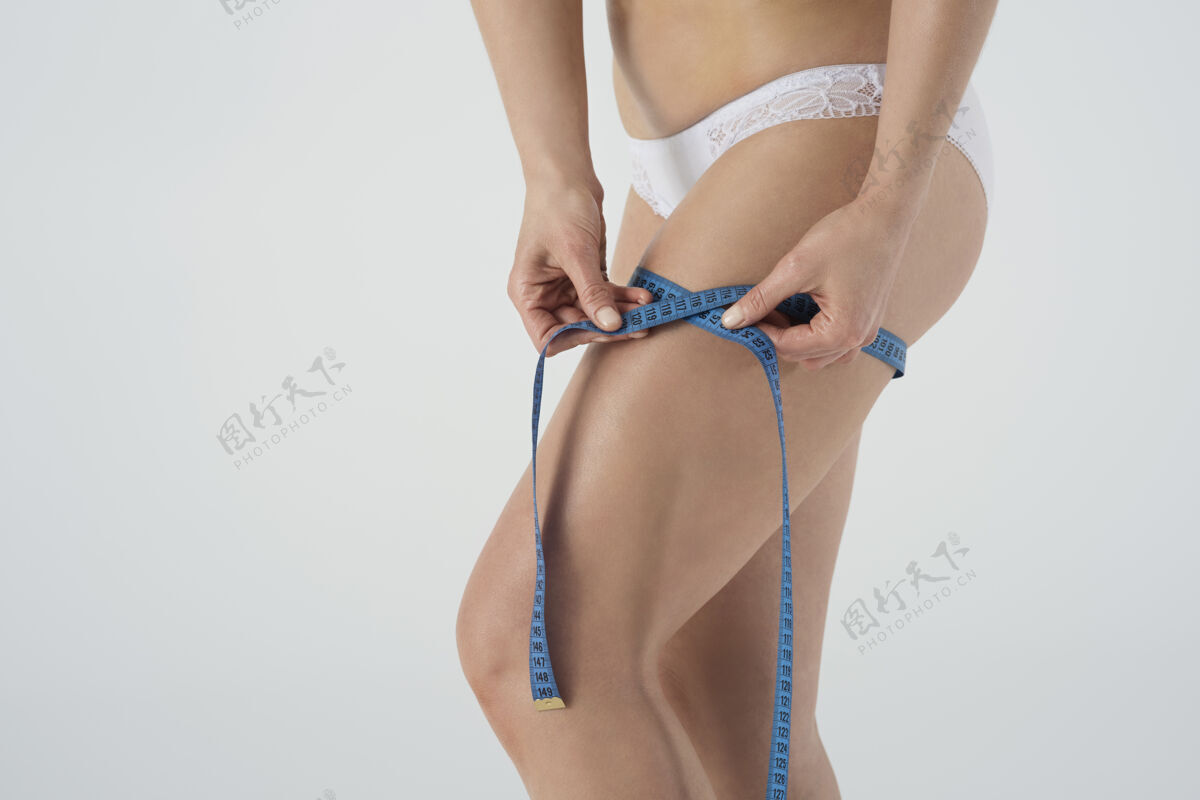 大腿快乐的女人穿着基本的内衣测量自己孤立测量女人身体护理