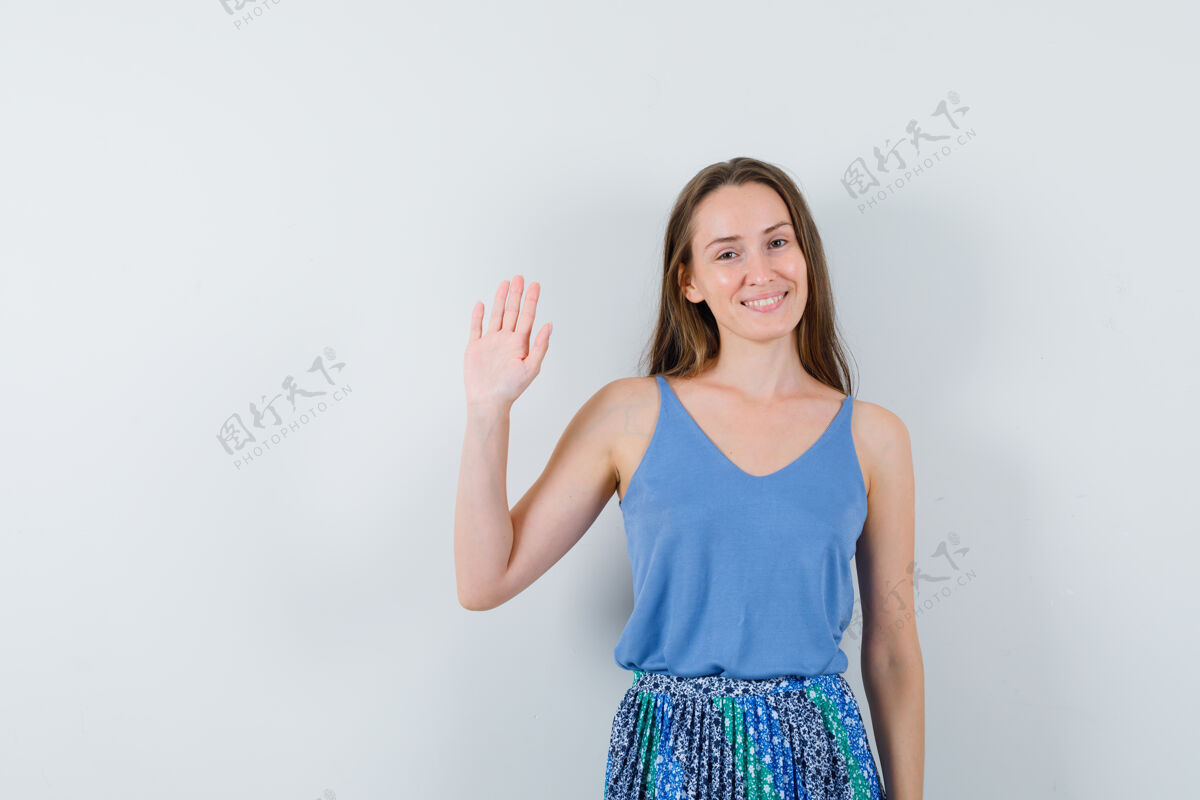 观众年轻的女士挥手告别蓝色衬衫 裙子 看起来很高兴前视图娱乐夜晚肖像