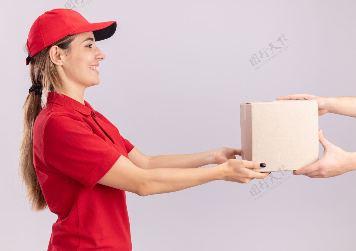 某人微笑着的年轻漂亮的女送货员 穿着制服 把名片盒给了一个被隔离在白墙上的人人感情微笑
