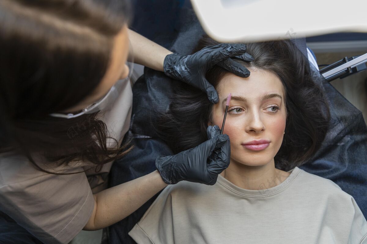 女人美容师正在为她的客户做眉毛护理女人客户美容