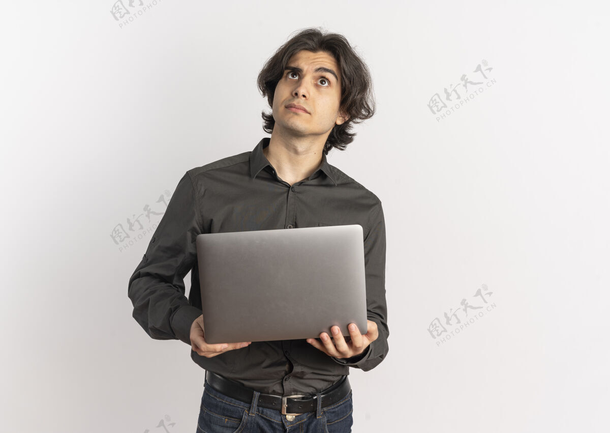 年轻年轻困惑英俊的白种人拿着笔记本电脑 在白色背景上孤立地抬头看 还有复印空间笔记本电脑迷茫帅气