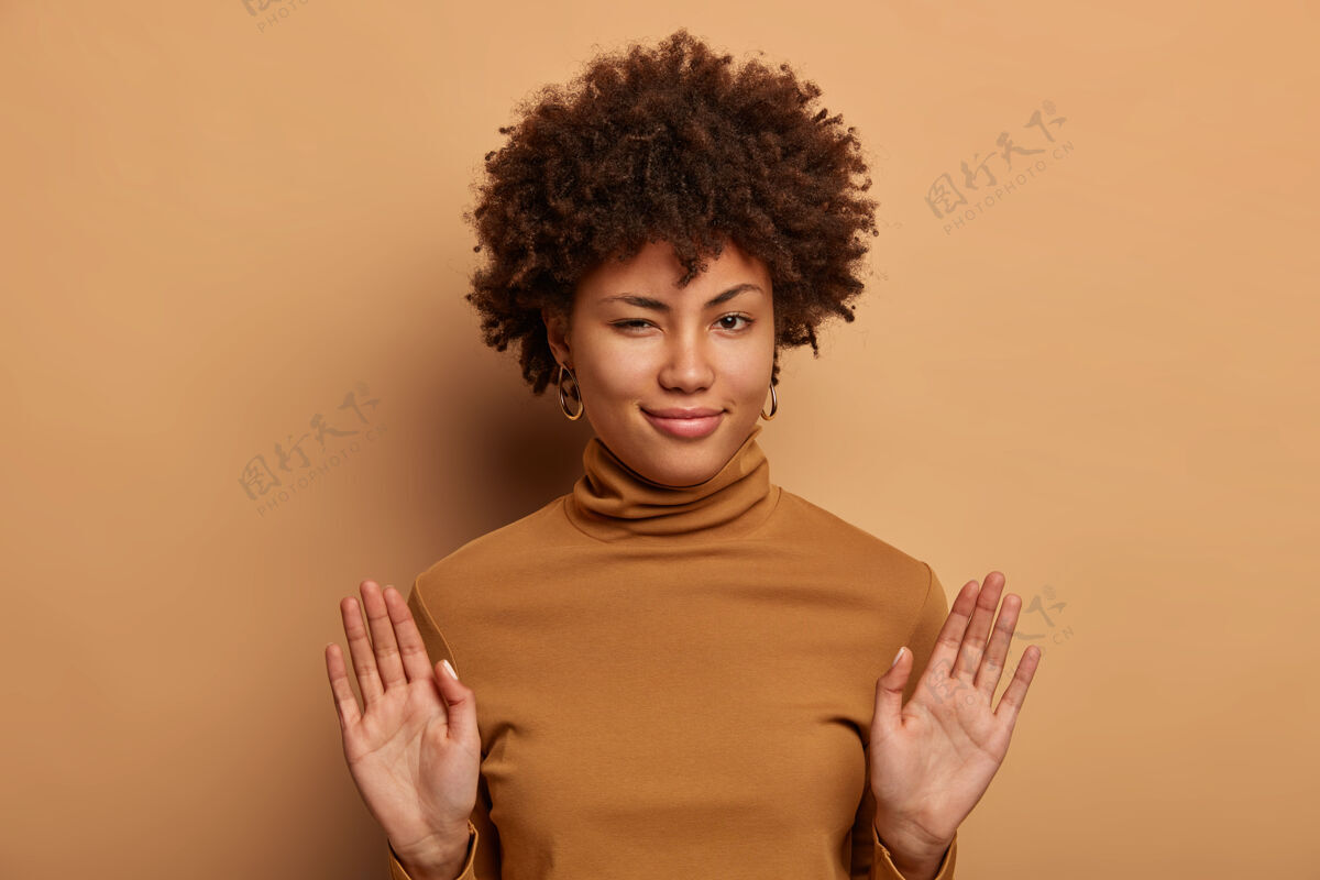 手掌可爱卷发女人的照片拒绝陌生的提议 掌心向前 有神秘的表情 穿着棕色马球衫 拒绝邀请 拒绝道歉手势禁止显示