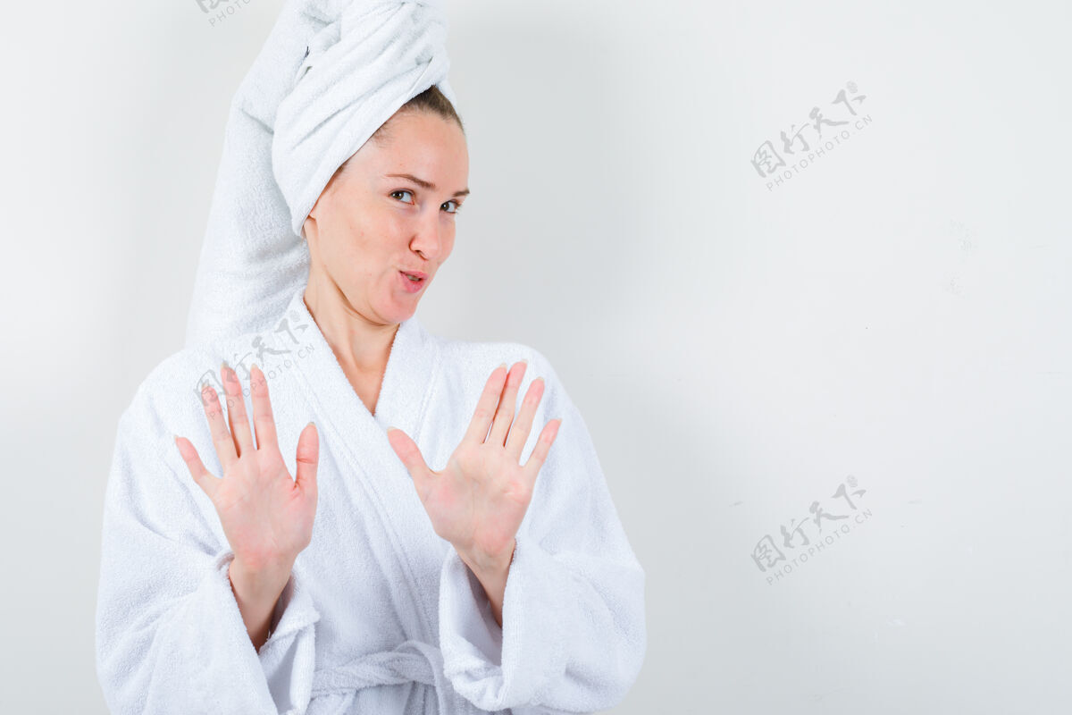 停止穿着白色浴衣 毛巾的年轻女士展示着停车姿势 看起来很理智 正前方的景色前面漂亮显示