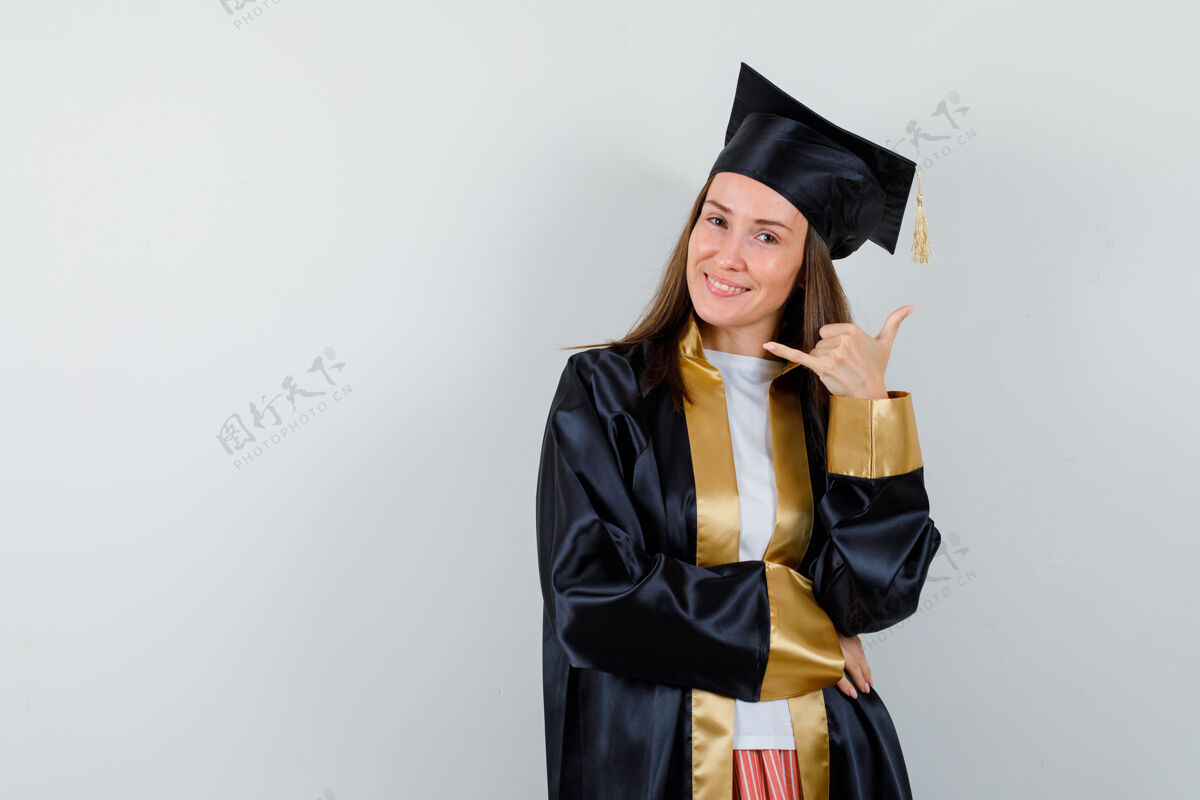 护理年轻的女毕业生穿着学院服 摆着电话姿势 看上去很高兴正面图皮肤学术肖像