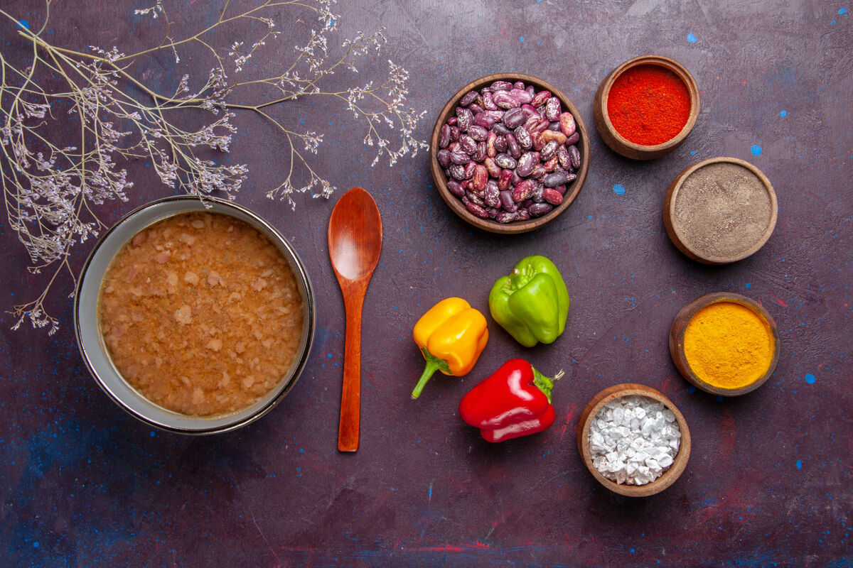 胡椒顶视图褐色的汤在盘子里用豆子和调味料放在深色的表面上汤菜饭食物菜油香料蔬菜观点