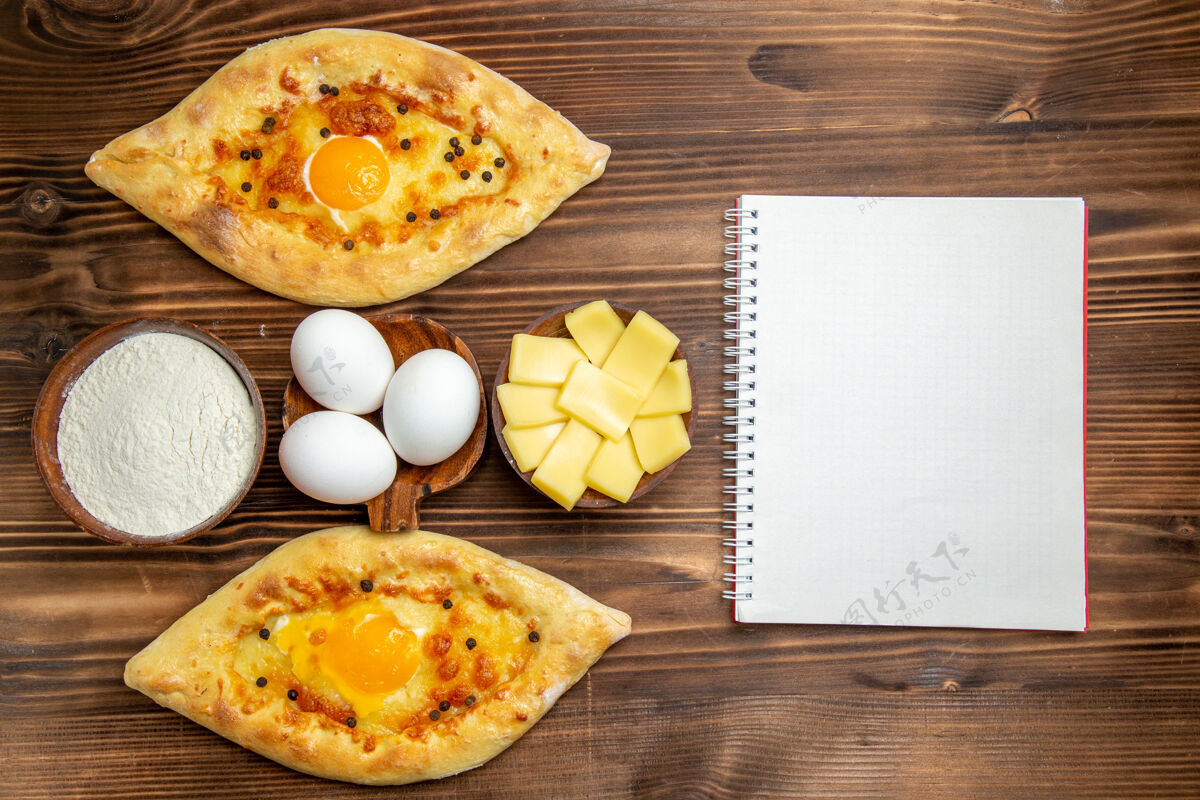 营养品顶视图烤鸡蛋面包刚从烤箱里拿出来 放在棕色木制桌子上 面团鸡蛋面包早餐面包面包生的面团
