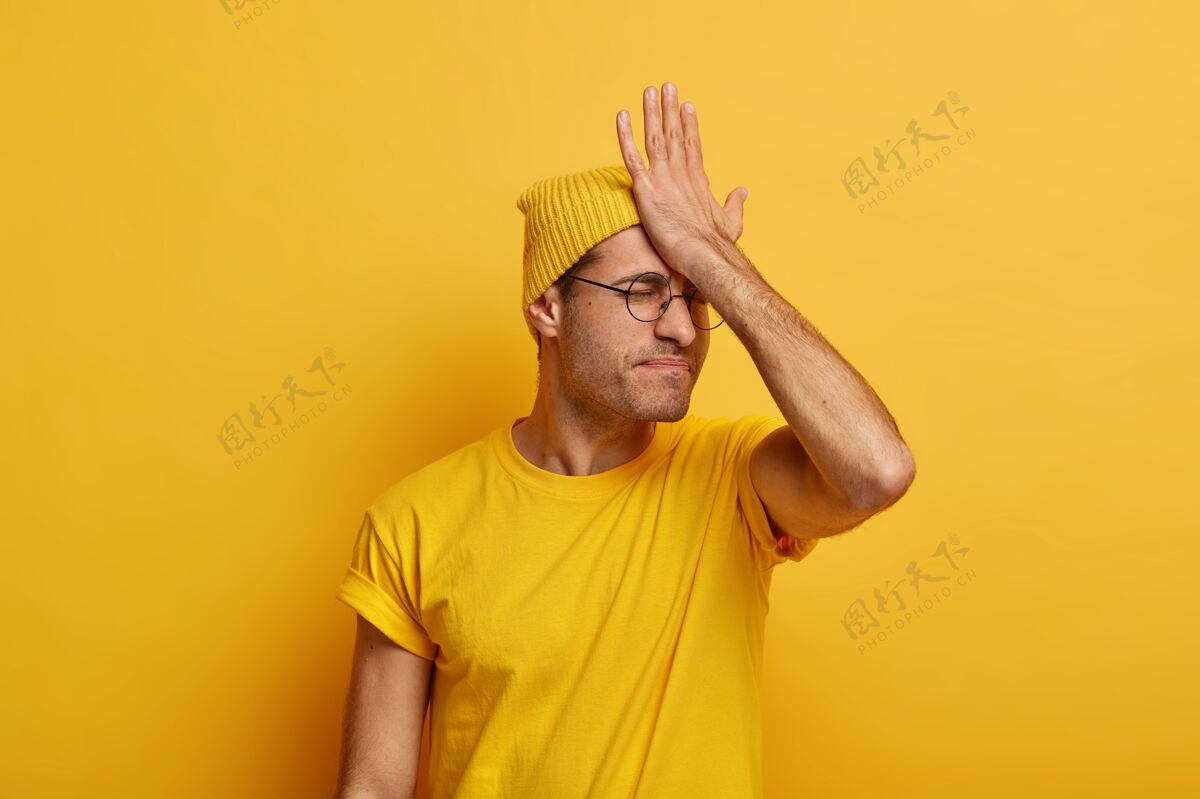 表情严肃的男人忘记了重要的会议 掌心打在额头上 有悔恨的感觉 记得关于任务 穿着休闲服 模特对着黄色的空间问题姿势眼镜