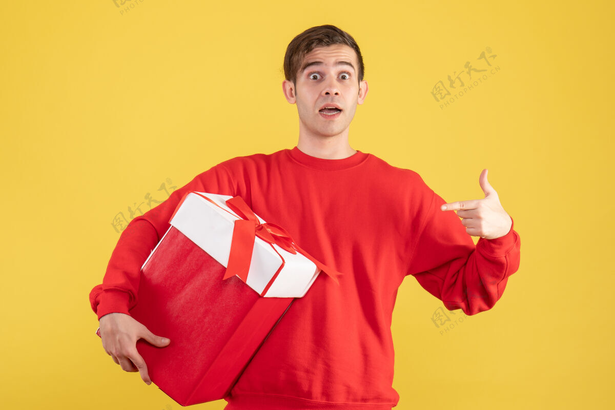 背景正面图：穿着红色毛衣的年轻人指着黄色背景上的自己漂亮成人前面