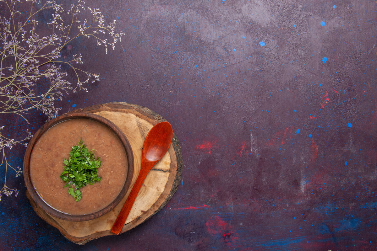 碗顶视图棕豆汤美味的煮熟的汤与绿色的深色背景蔬菜晚餐汤餐食品绿色容器杯子