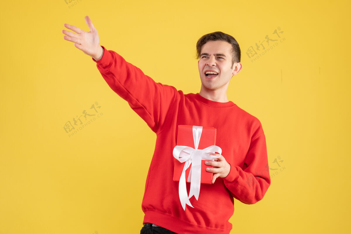 专业前视图穿着红色毛衣的年轻人招呼黄色背景上的人男人男性微笑